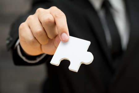 Businessman holding white jigsaw piece