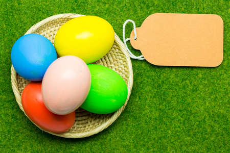 Easter eggs and paper label on green grassの写真素材