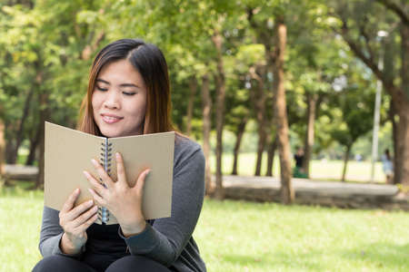 Asian woman reading a book in the park