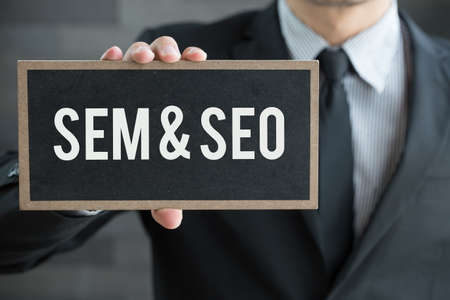 SEM and SEO, message on blackboard and hold by businessman