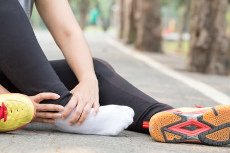 Sports injury. Woman with pain in ankle while jogging