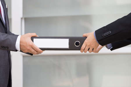 Businessman delivering documents to businessmanの写真素材