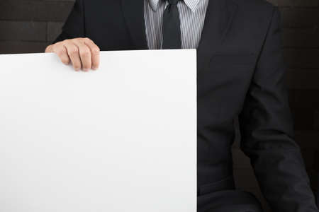 Hand of businessman showing white paperの写真素材