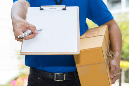 Delivery Man holding parcel and giving pen to clientの写真素材