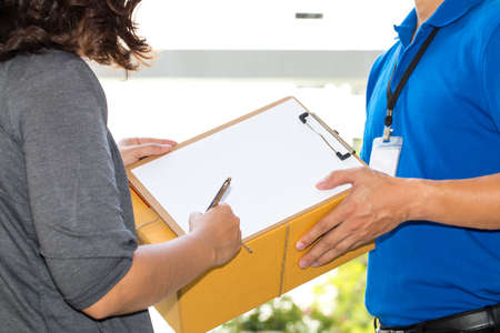 Woman hand signing receipt of delivered package. Delivery concept. Receiving packageの写真素材