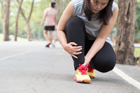 Sports injury. Woman with pain in ankle while joggingの写真素材
