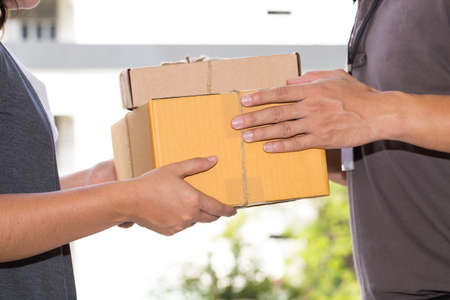 Woman hand accepting a delivery of boxes from deliverymanの写真素材