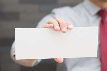 Hand of businessman showing white paperの写真素材