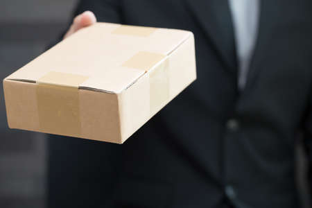 Businessman in suit giving brown box to someoneの写真素材