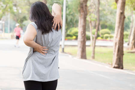 Women have a backache while jogging. Sport injury conceptの写真素材