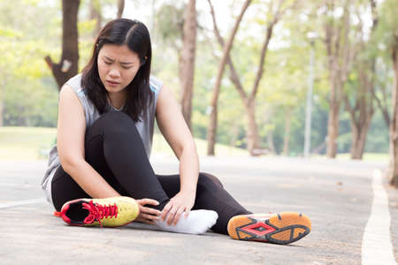 Sports injury. Woman with pain in ankle while joggingの写真素材