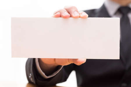 Hand of businessman showing white paperの写真素材