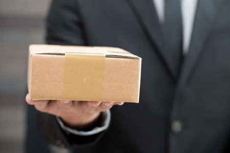 Businessman in suit giving brown boxの写真素材