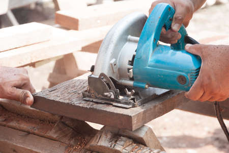 Carpenter cutting wood by circular saw
