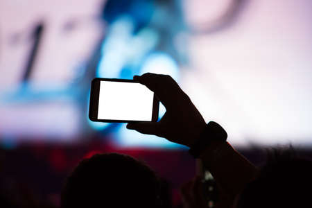 Hand with a smartphone records luxury party with blank white screen