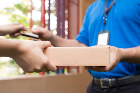 Woman hand accepting a delivery of boxes from deliverymanの写真素材