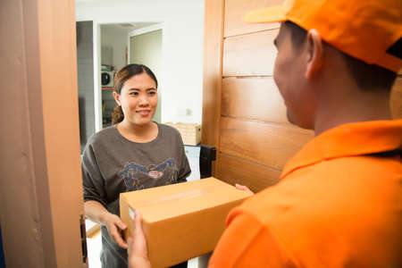Asian woman accepting a delivery of boxes from deliverymanの写真素材