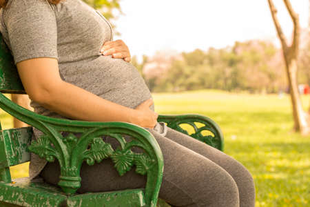 Pregnant woman sitting on a bench in the gardenの写真素材