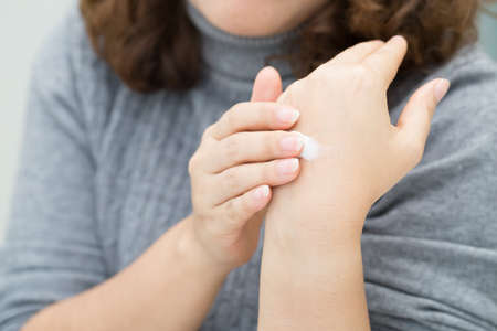 closeup of female hands applying hand creamの写真素材