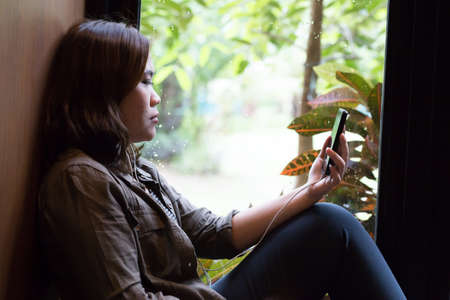 Broken heart and listening sad music at the window in roomの写真素材