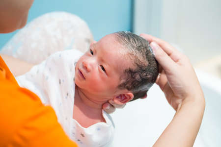Asian newborn baby boy taking a shower and wash hair by mother in the bathroom, 9 days of life, child kid conceptの写真素材