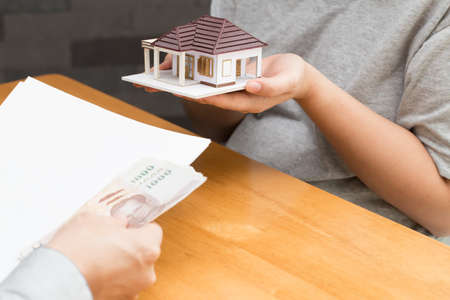 Women brought the house to the bank and received money from the banker, Mortgage home concept