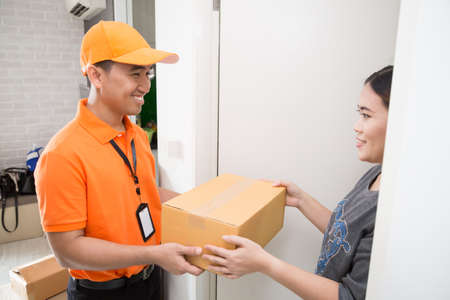 Asian woman accepting a delivery of boxes from deliveryman