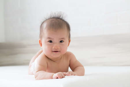 Happy laughing baby boy on white bedの写真素材