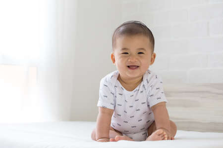 happy little baby boy sitting on the bed at home