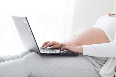 Pregnant women use internet by laptop for seeking pregnancy related informationの写真素材