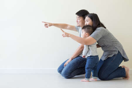 Happy asian family looking away and pointing upの写真素材