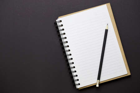Top view of white paper and pencil on black background with empty space for text information