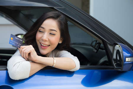 Happy young Asian woman holding payment card or credit card and used to pay for gasoline, diesel,...