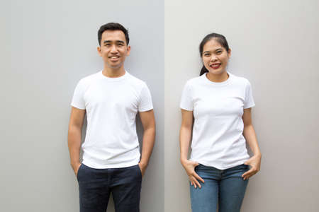 Young Asian couple wearing white t-shirt on grey color wall, Mock up template for design print conceptの写真素材