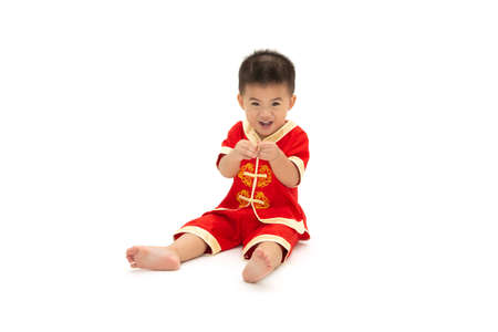Asian baby boy sit and show mini heart with fingers and wearing traditional Chinese suit isolated on white background, Dress up for Chinese new year festival concept, One year six month infant modelの写真素材