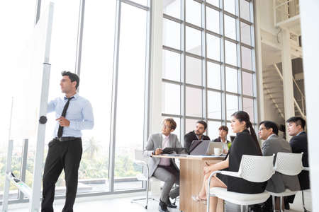 Business executive delivering a presentation to his colleagues during meeting. Briefing project in...