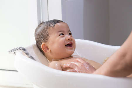 Asian baby boy taking a bath by mom. Hygiene and care for young children conceptの写真素材