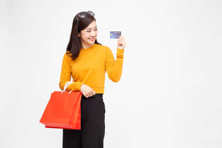 Portrait of a happy young woman holding shopping bags and credit card isolated over white...