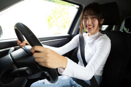 Asian women driving a car and smile happily with glad positive expression during the drive to travel...