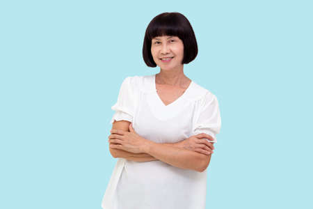 Portrait of asian senior woman with arms crossed isolated over blue background, Elderly woman...