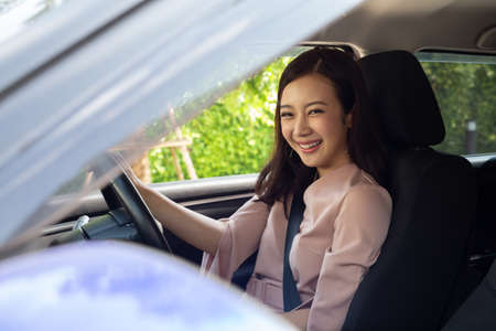 Happy Asian women driving a car and smile with glad positive expression during the drive to work office in workdayの写真素材