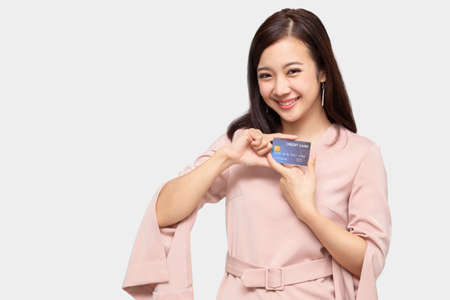 Young beautiful Asian woman smiling, showing, presenting credit card for making payment or paying online business, Pay a merchant or as a cash advance for goods, Cardholder or A person who owns a cardの写真素材