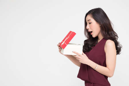 Asian woman holding and showing red gift box and open the box with wow surprise expression isolated on white backgroundの写真素材