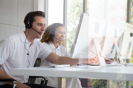 Operator service desk consultant talking and smiling on hands-free phone. Customer support agent or call center with headset works on desktop computer concept.の写真素材