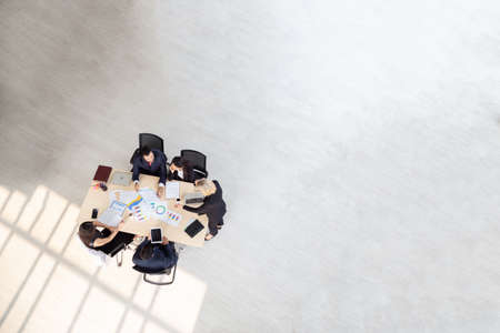 Top view of group of multiethnic busy people working in an office, Aerial view with businessman and businesswoman sitting around a conference table with blank copy space, Business meeting conceptの写真素材
