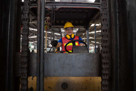 Asian forklift driver at workplace in factory and looking at the camera