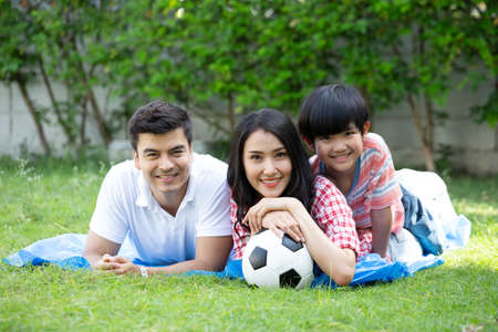 Family playing football or soccer in green garden together their leisure time at summer holiday
