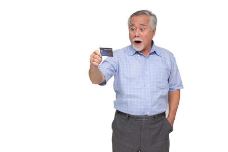 Portrait of excited screaming senior asian man standing and holding credit card isolated over white...