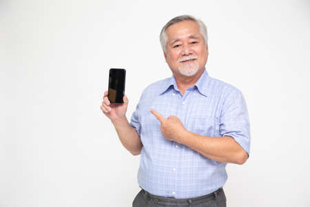 Portrait of a Asian senior man showing or presenting mobile phone application and pointing finger to...
