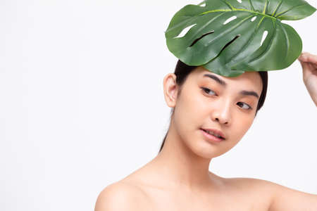 Happy beautiful young Asian woman with clean fresh skin and green leaves, Girl beauty face care, Facial treatment and cosmetology spa conceptの写真素材